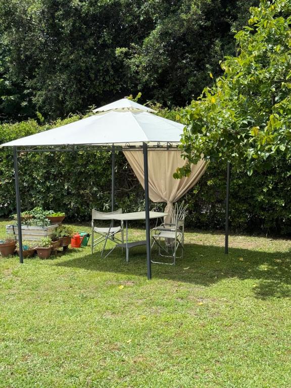 a tent with a table and a chair under it at Casolare De Ranieri - appartamento in villa bifamiliare a 500m dal mare in Marina di Massa