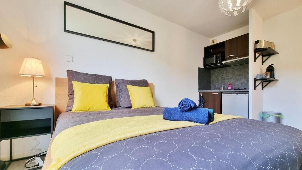 - une chambre dotée d'un grand lit avec des oreillers jaunes et bleus dans l'établissement Le Campus - Proche centre - Rénové - RBNB, à Mulhouse