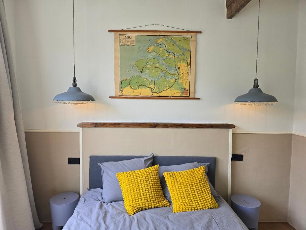 1 dormitorio con 1 cama con almohadas amarillas y 2 luces en Herberg Hanenberg, en Wissenkerke