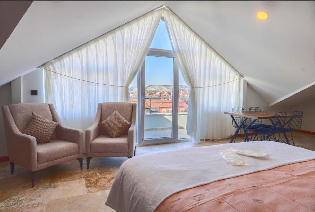 a bedroom with two chairs and a bed and a window at Avanos Ertaş Konukevi in Avanos