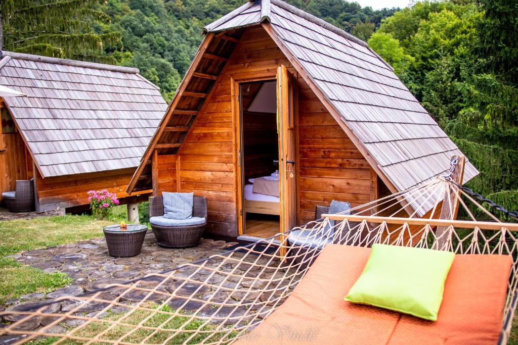 a hammock in front of a wooden house at Glamping Zeleni turizem in Makole