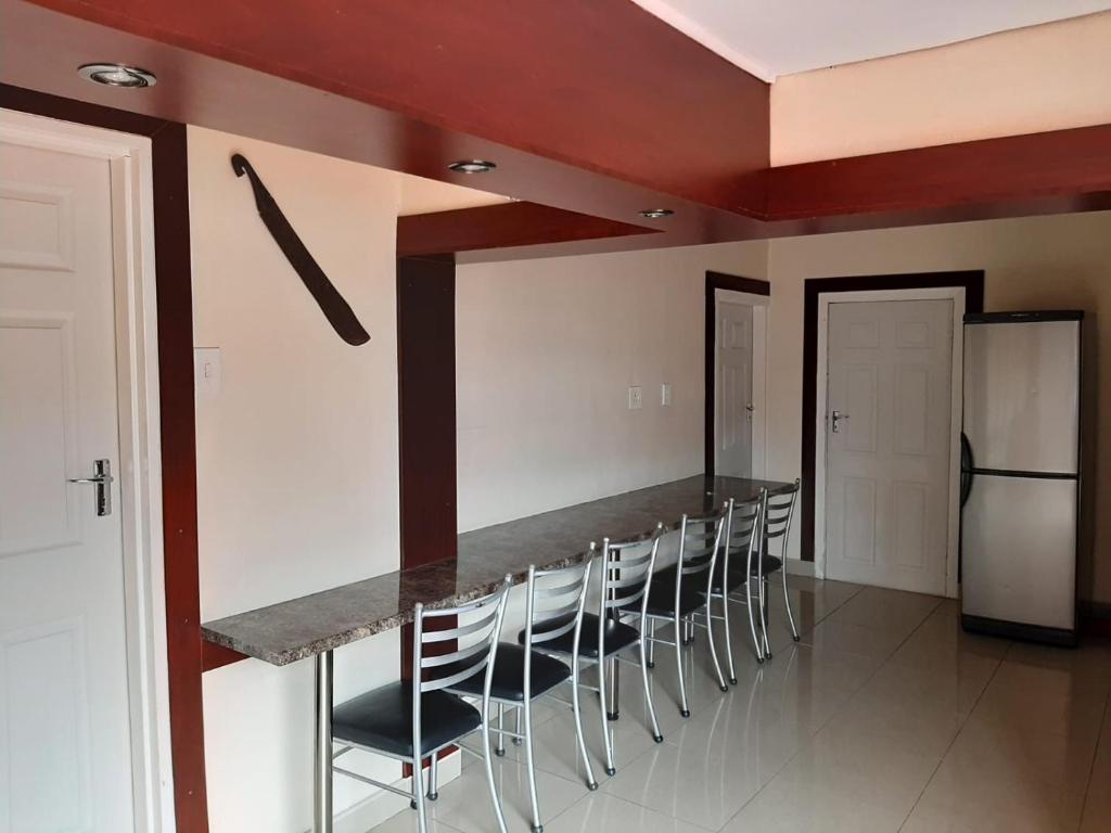a kitchen with a bar with chairs and a refrigerator at Faraaz BnB in Ladysmith