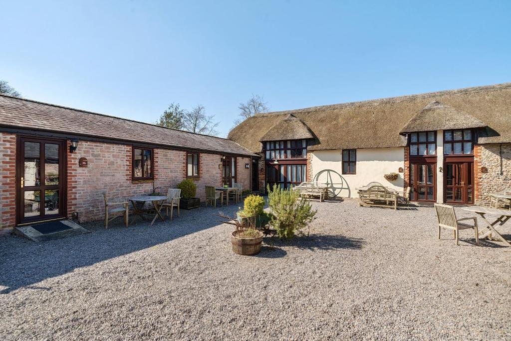 a courtyard of two brick buildings with tables and chairs at Berehayes Cottages in Whitchurch Canonicorum