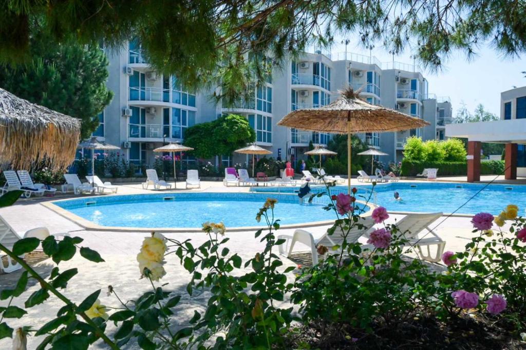 a large swimming pool with chairs and an umbrella at Atlantis Getaway in Burgas City