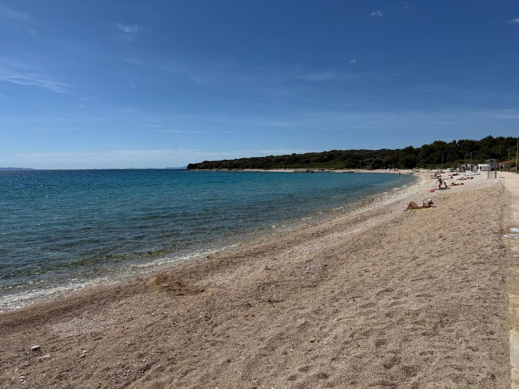 a beach with people laying on the sand and the water at Ogi Seaside Gajac in Novalja