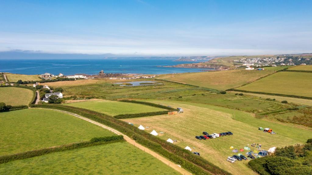 an aerial view of a field with the ocean at Cool Cow Glamping in Hope-Cove