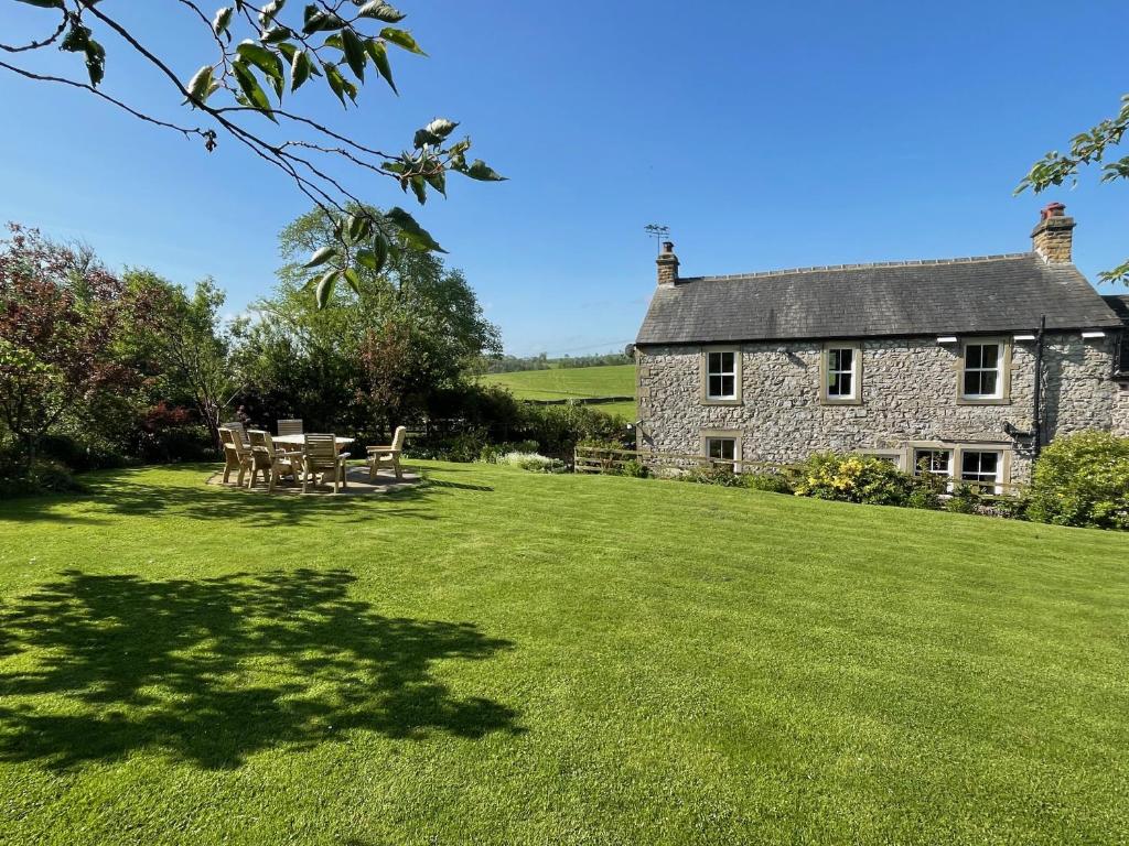 a stone house with a table and chairs in a yard at Luxurious Granny House Bell Busk in Malhamdale in Skipton