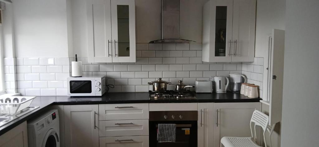 a kitchen with white cabinets and a black counter top at Mary's Place in Plumstead