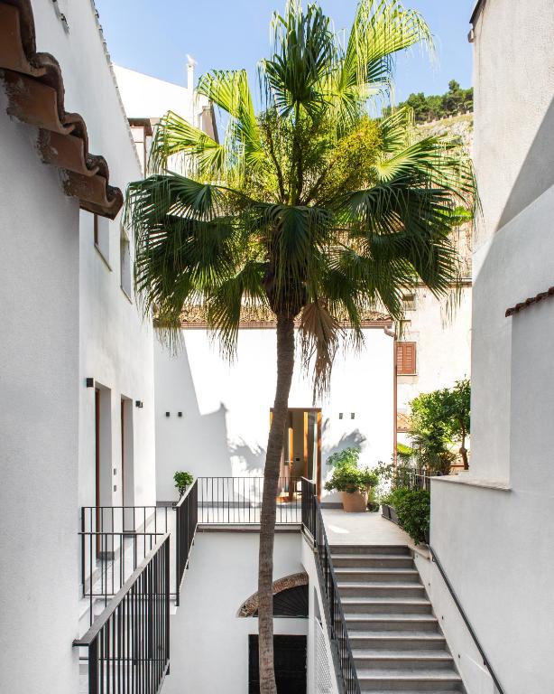 a palm tree on the side of a building with stairs at Palazzo Botta Suites in Cefalù