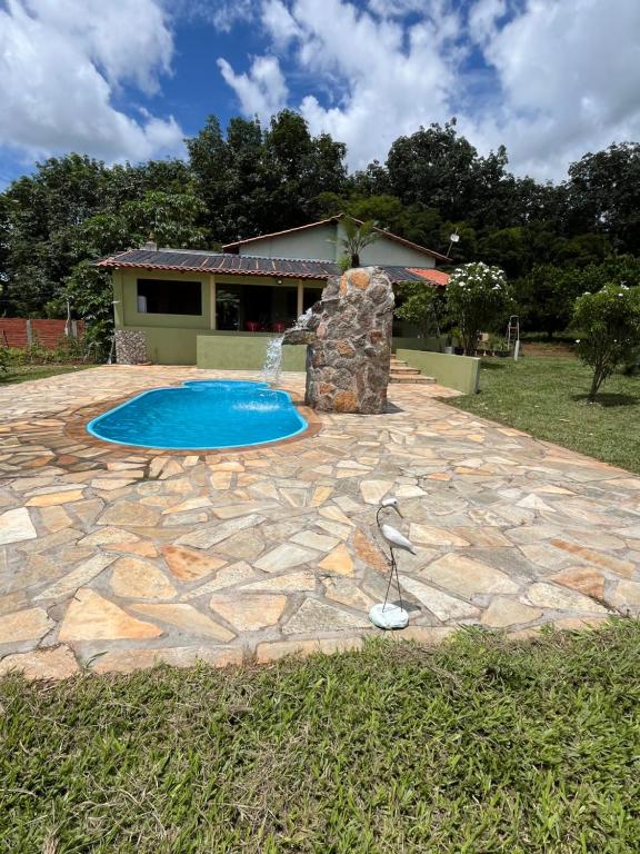 a stone patio with a pool and a water fountain at Chácara Recanto Ribeiro in Pirenópolis