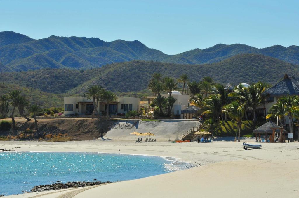 a beach with palm trees and houses and the ocean at Rancho De Costa by Cabo Villas in La Paz