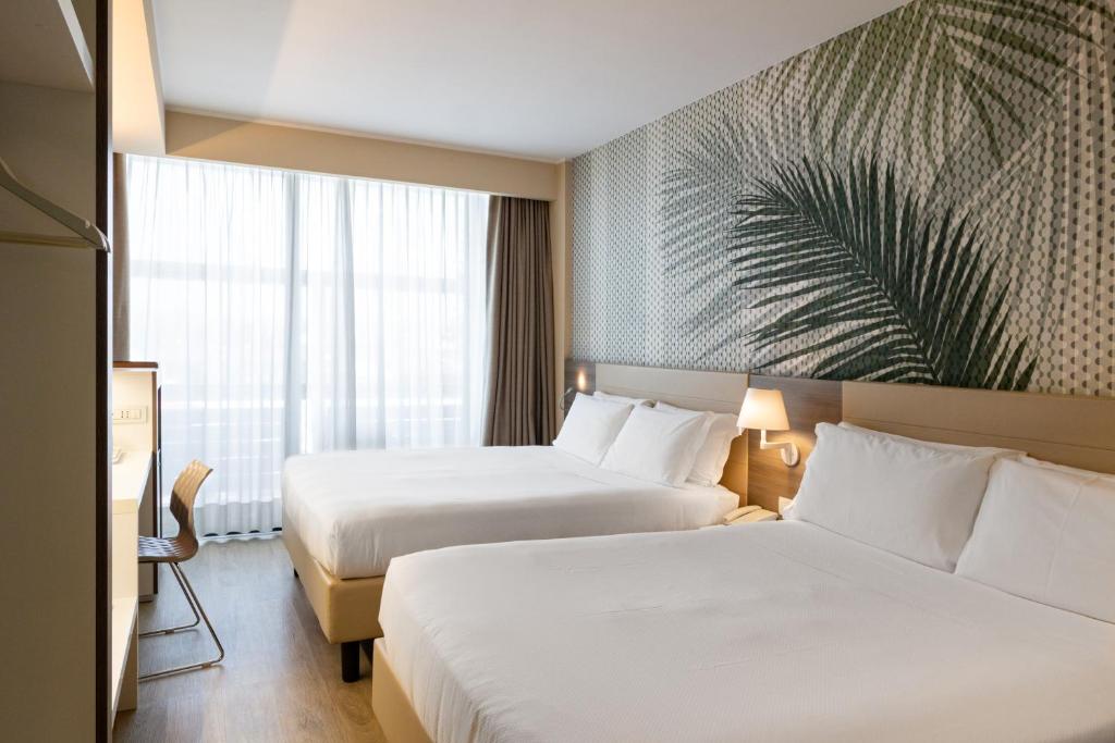 a hotel room with two beds and a large window at Enjoy Garda Hotel in Peschiera del Garda