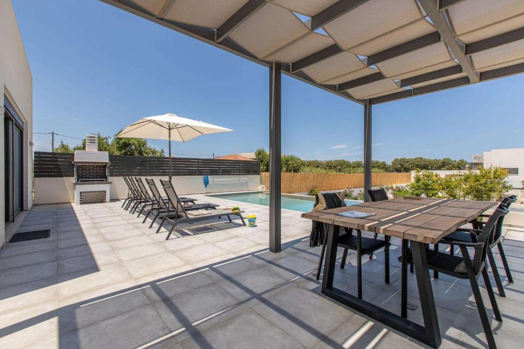 a patio with a table and chairs and a pool at Sage Villa by Vintage Travel in Tavronitis