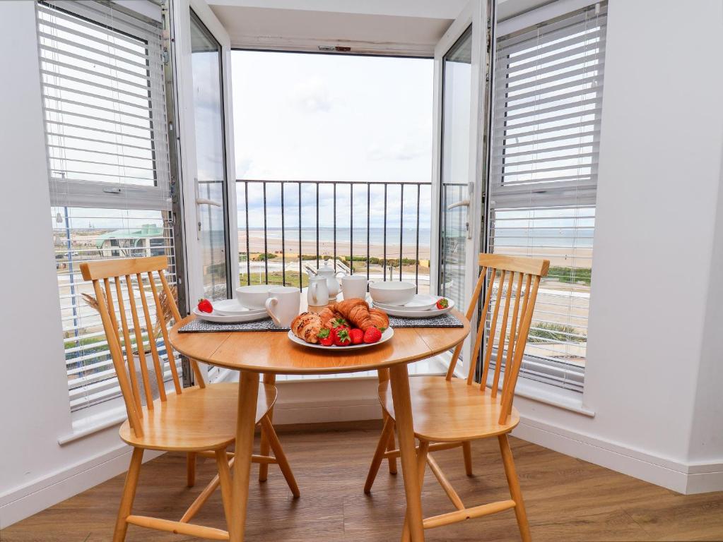 a dining room with a table and chairs and windows at Glenholme Apartment 6 in Redcar