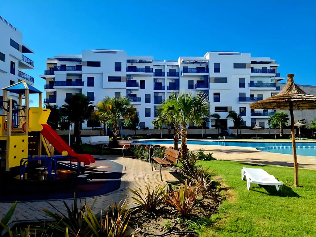 a resort with a slide and a playground and a building at Ground floor apartment,facing swimming pool, wifi , air conditioner in Martil