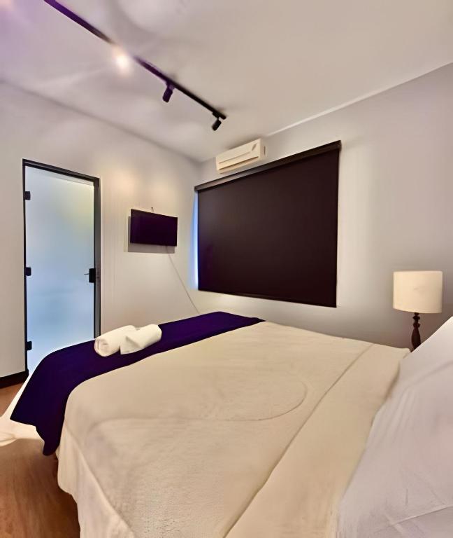 a bedroom with a large bed and a flat screen tv at KiTNETcompleta ótima localização in Curitiba