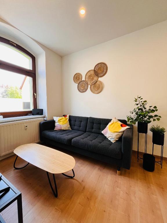 a living room with a black couch and a table at Makro Apartment Großenhain in Großenhain