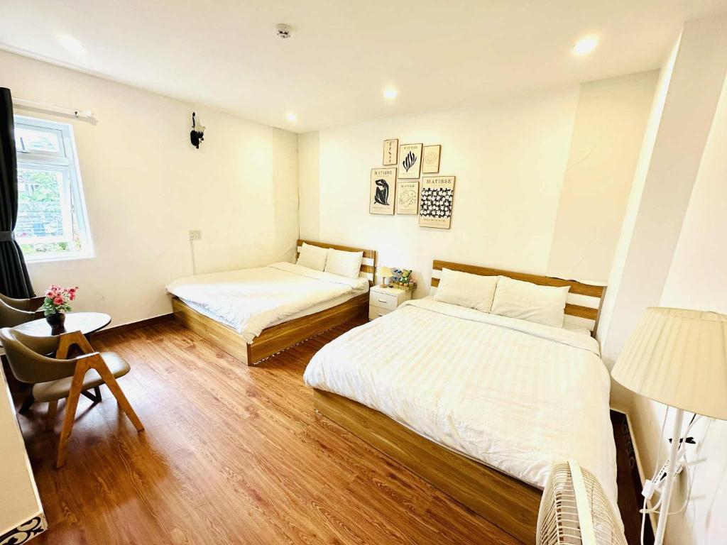 a bedroom with two beds and a desk and a lamp at Nhà Của Nắng - Homestay Đà Lạt in Da Thanh