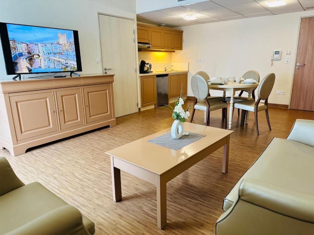 un salon avec une télévision, une table et des chaises dans l'établissement T2 à proximité Grands Buffets, à Narbonne