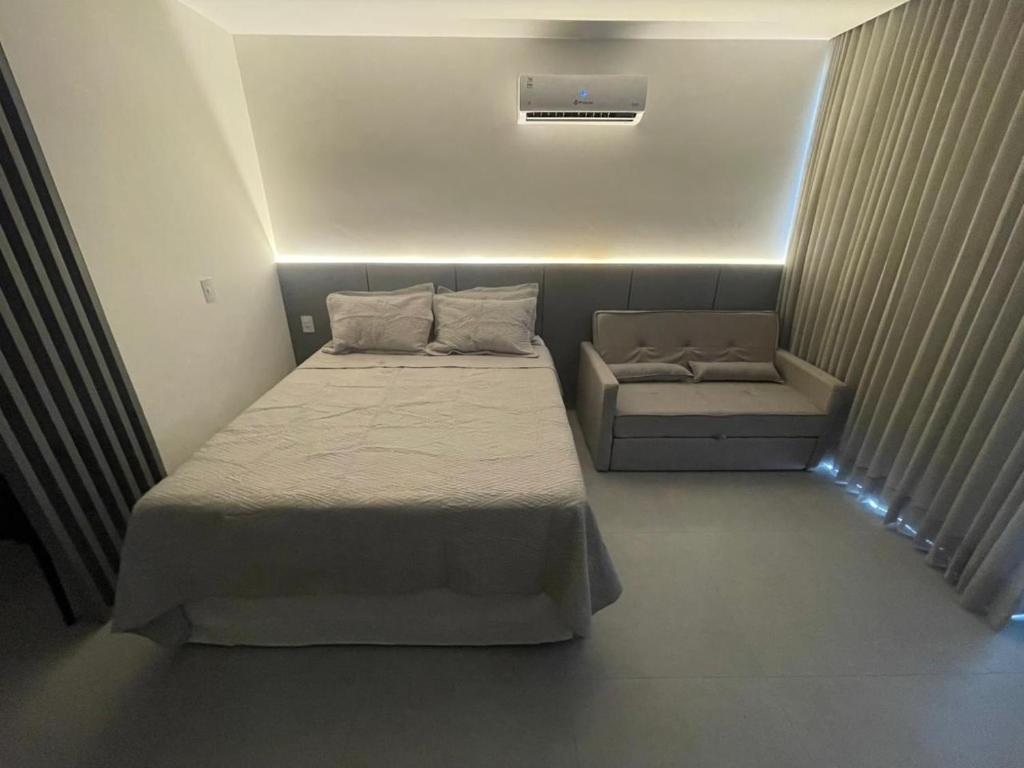 a small bedroom with a bed and a chair at Studio306 - Simple 350 in João Pessoa