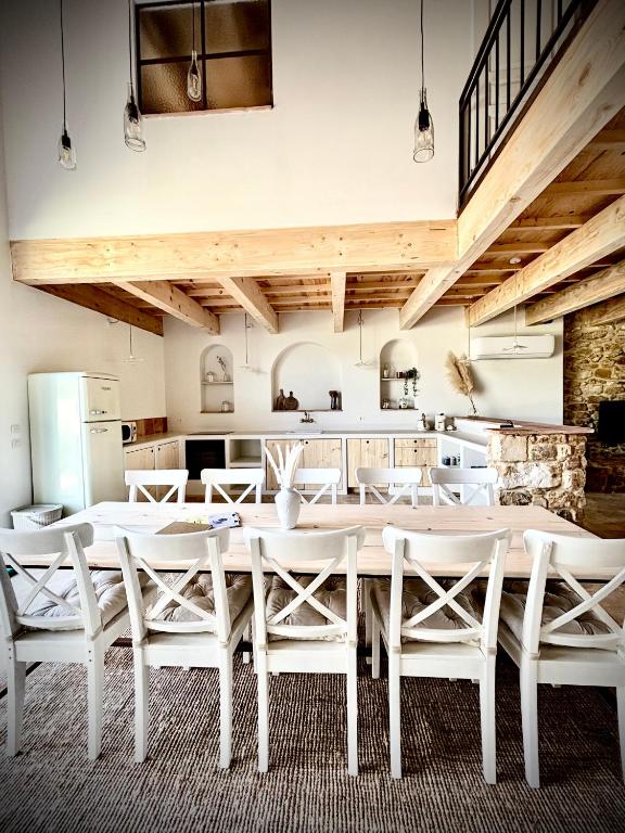 une salle à manger avec des tables blanches et des chaises blanches dans l'établissement Gîte dans un domaine - La cave du vigneron - Uzès - 10 personnes, à Baron