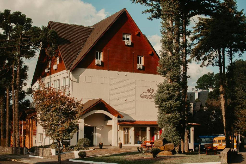 a large white building with a brown roof at Hotel Colina São Francisco in Gramado