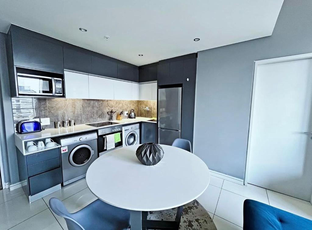 a kitchen with a white table and a white kitchen at Stunning City View Apartment Sandton City in Johannesburg