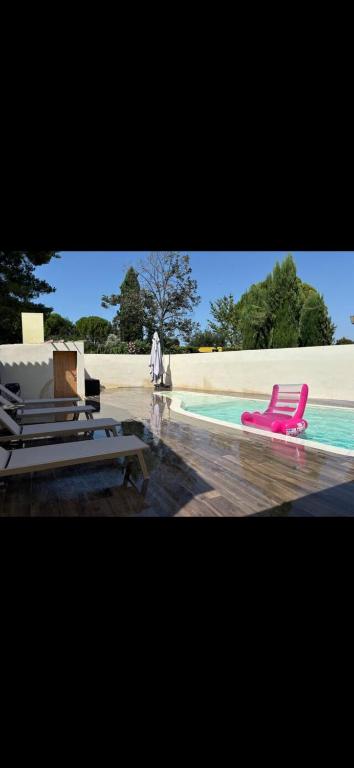une piscine avec une chaise longue rose et une piscine dans l'établissement Villa , piscine , jacuzzi 10 min de la mer, à Lunel
