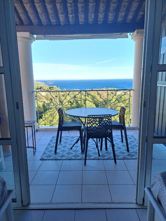 une table et des chaises sur un balcon avec vue sur l'océan dans l'établissement Vue mer panoramique au Cap Esterel T2, à Saint-Raphaël