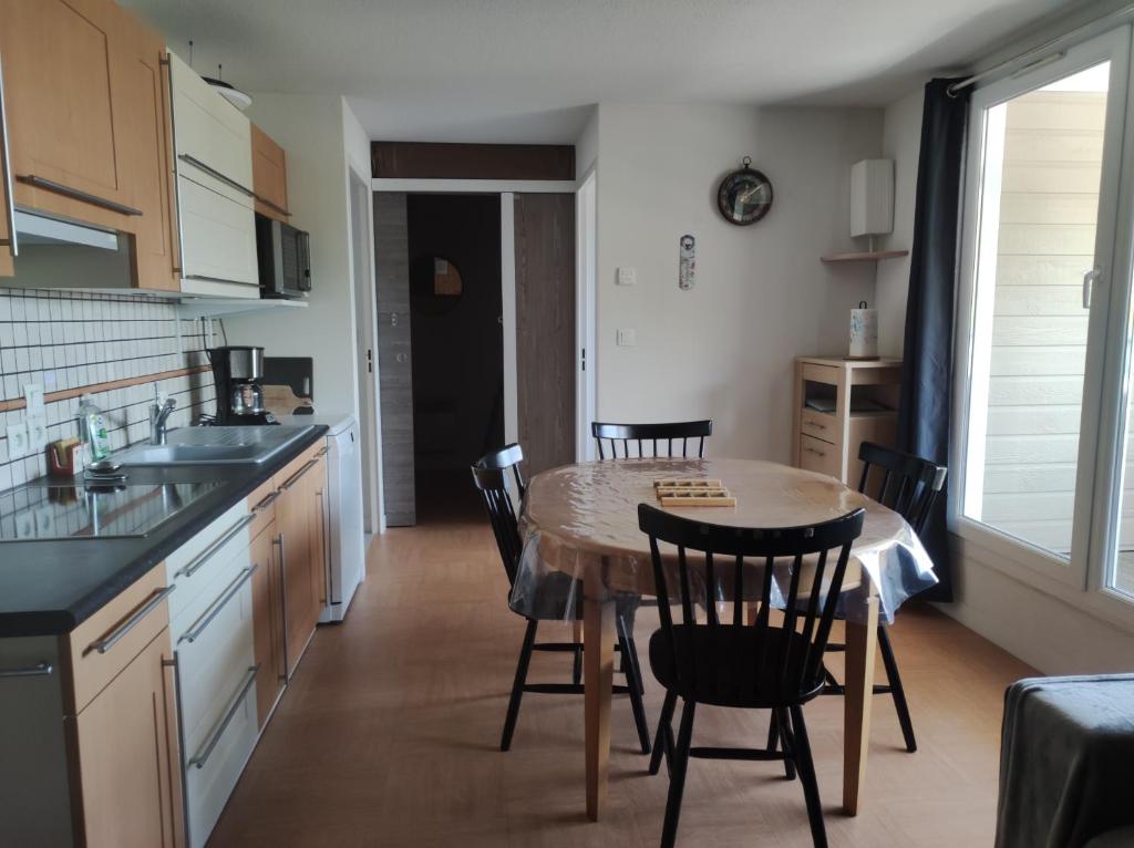 une cuisine avec une table et des chaises dans une cuisine dans l'établissement Au pied des piste T4 51m2 avec garage Le Pavin, à Besse-et-Saint-Anastaise