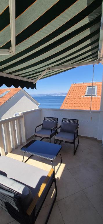 a patio with four tables and chairs on a balcony at APARTMENTS BRUNO 3 - two-room penthouse apartment - wonderful view of the sea - the best location, first row to the beach - 10 minutes from Supetar ferry port - free secured parking - facilities nearby in Sutivan