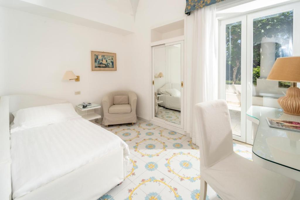 a white bedroom with a bed and a chair at Hotel Bellavista in Anacapri