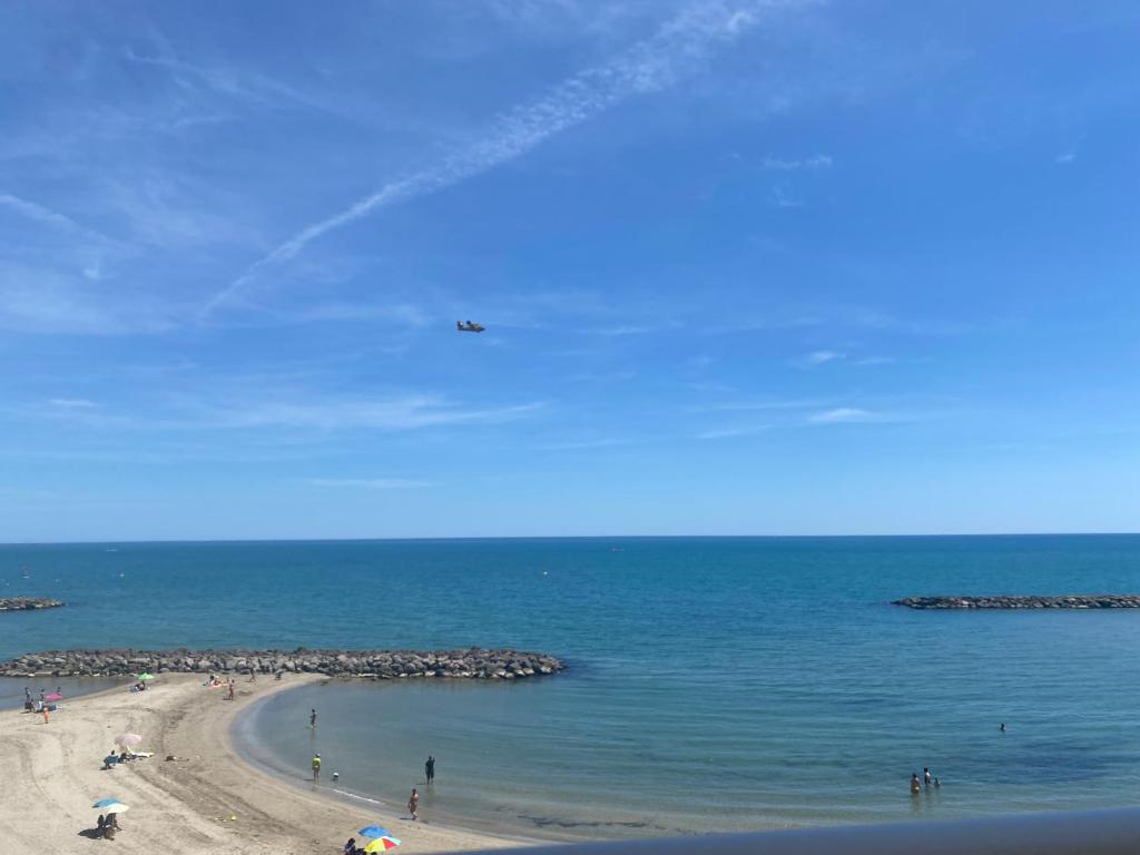 Un avion survole une plage avec des gens dans l'établissement Un balcon entre azur et mer - Palavas les Flots, à Palavas-les-Flots