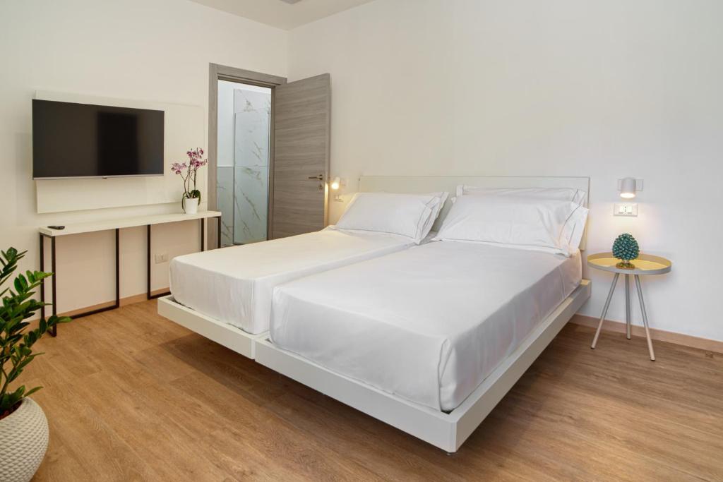 a white bedroom with a white bed and a television at Ella Suites Apartments in Terrasini