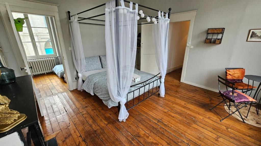 - une chambre avec un lit à baldaquin et du parquet dans l'établissement Les Jardins de Baudimont 4p apartment, à Arras