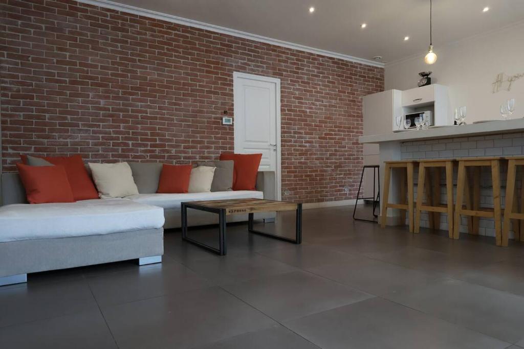 un salon avec un canapé et un mur de briques dans l'établissement Lenoir magnifique maison 8 pers avec terrasse, à Reims