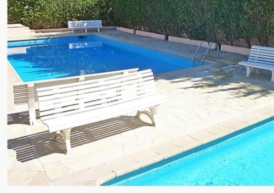 un banc blanc installé à côté d'une piscine dans l'établissement App 200 m mer, à Saint-Aygulf