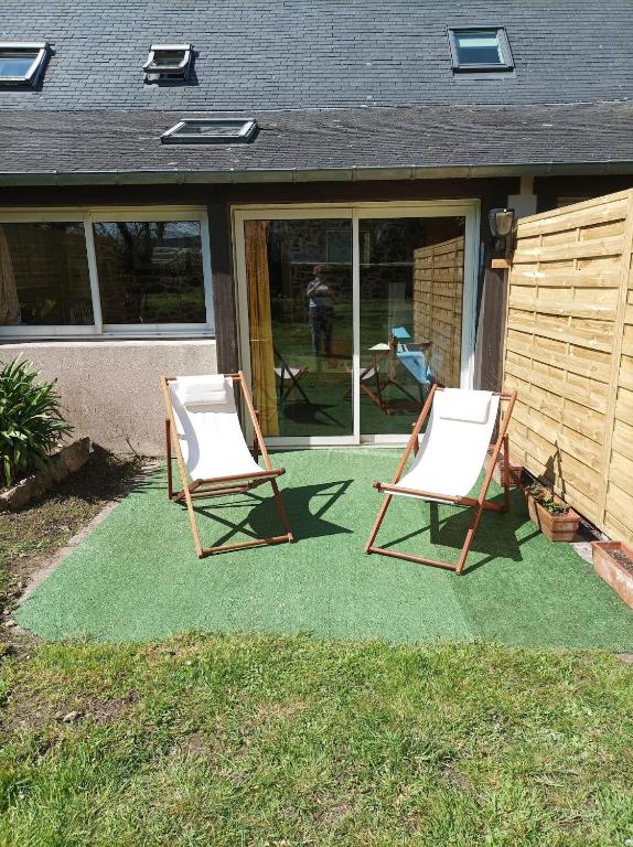 deux chaises assises sur une pelouse devant une maison dans l'établissement Maison de pêcheur, à Perros-Guirec
