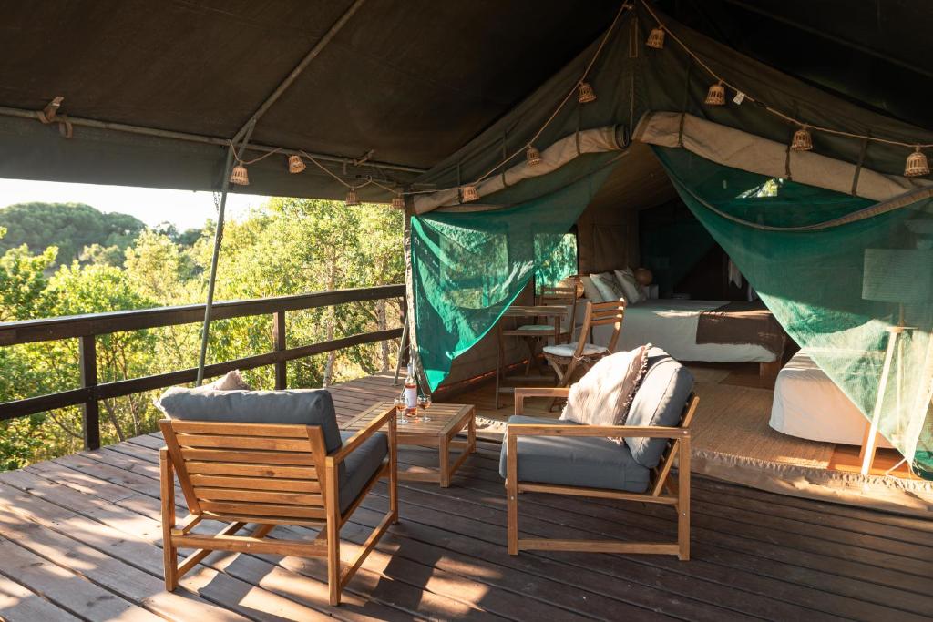 a tent with chairs and a table on a deck at Eco Glamping Portugal Nature Lodge in São Luis