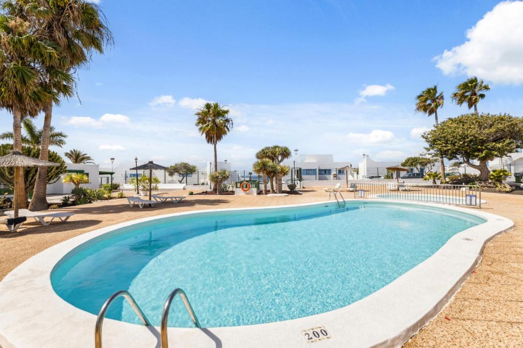 a large swimming pool with palm trees in a resort at Apartamento BANDAMA nº 5, recién renovado, newly renovated bungalow, Los Pocillos, Tías in Puerto del Carmen