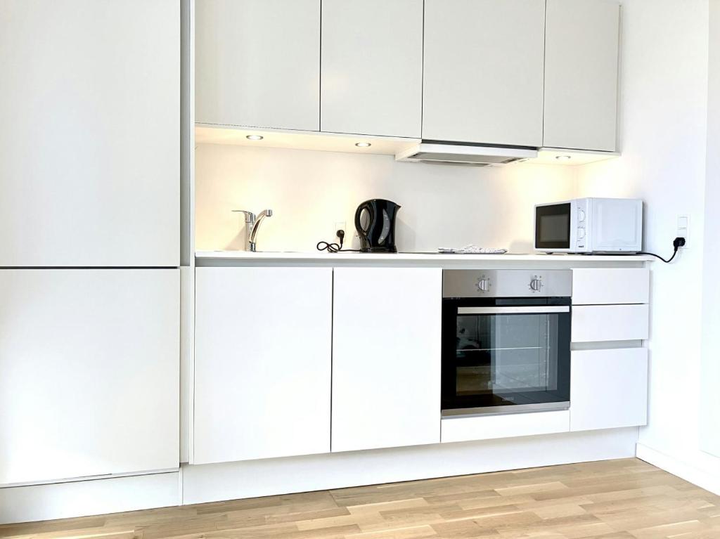 a white kitchen with white cabinets and a microwave at Convenient Apartment for 2 in Aarhus