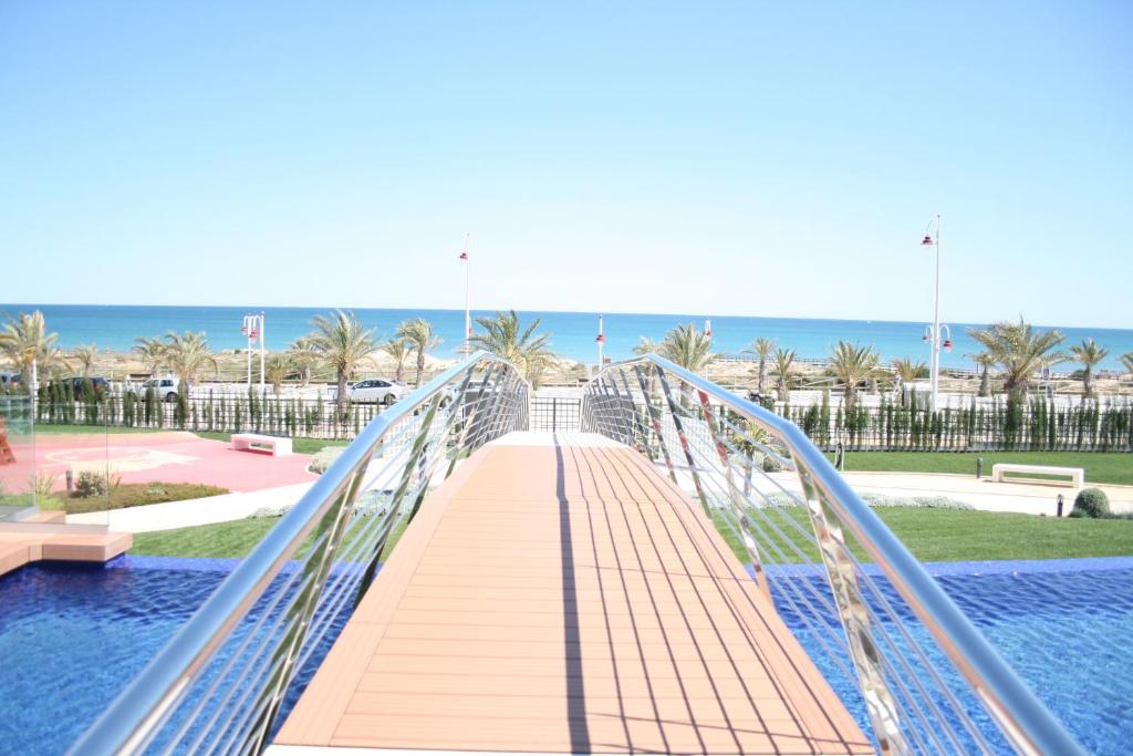 uma ponte pedonal sobre uma piscina na praia em Ocean View Apartment em Arenales del Sol