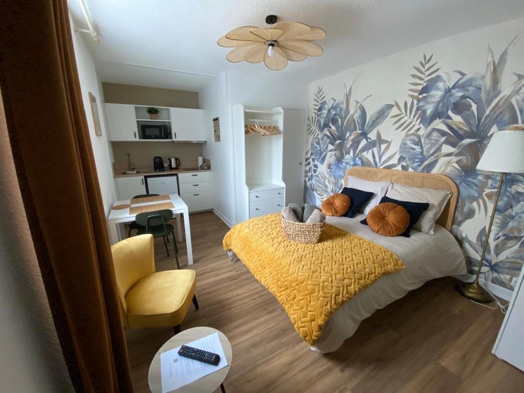 une chambre avec un lit avec une couverture jaune et une cuisine dans l'établissement Agréable Studio Caen Venoix, à Caen