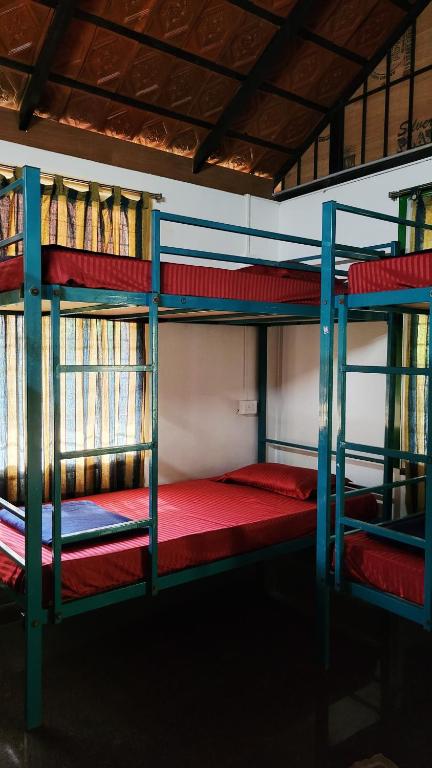 オーロヴィルにあるHostelExp, Auroville - A Rural Retreat Experienceの赤いシーツを使用した二段ベッド2組が備わる客室です。