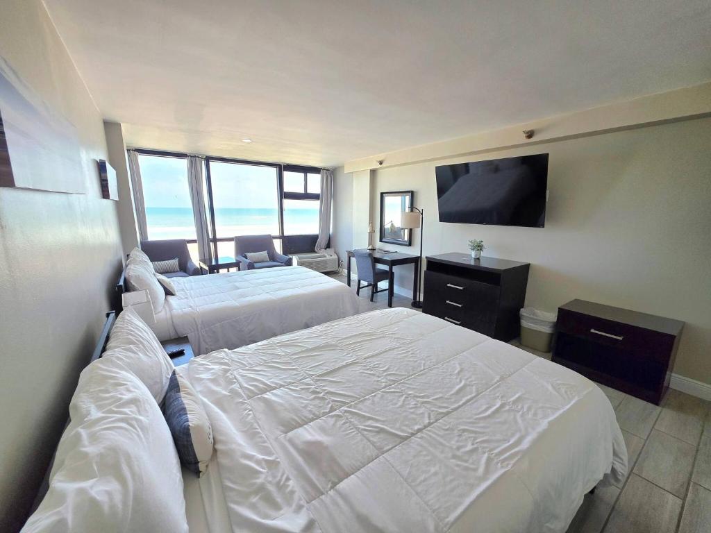 Una habitación de hotel con dos camas y un televisor de pantalla plana. en Oceanfront Studio 2 Queen beds kitchenette & pool, en Daytona Beach