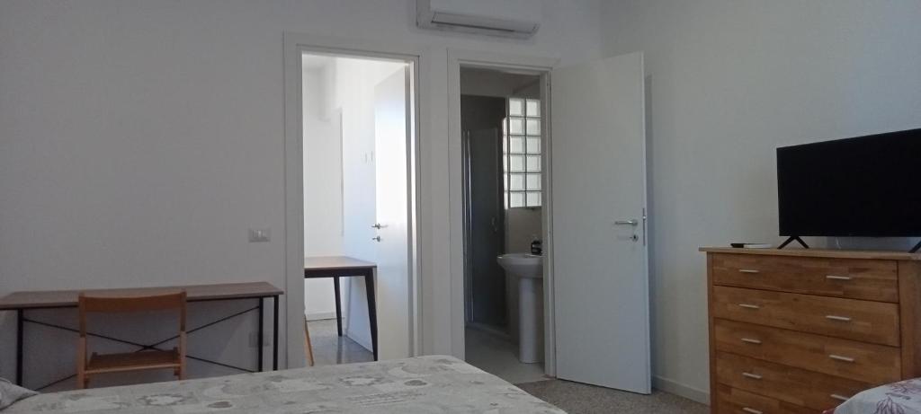 Un dormitorio con una cama, una cómoda y un televisor. en Cinghiale Bianco, en Cagliari