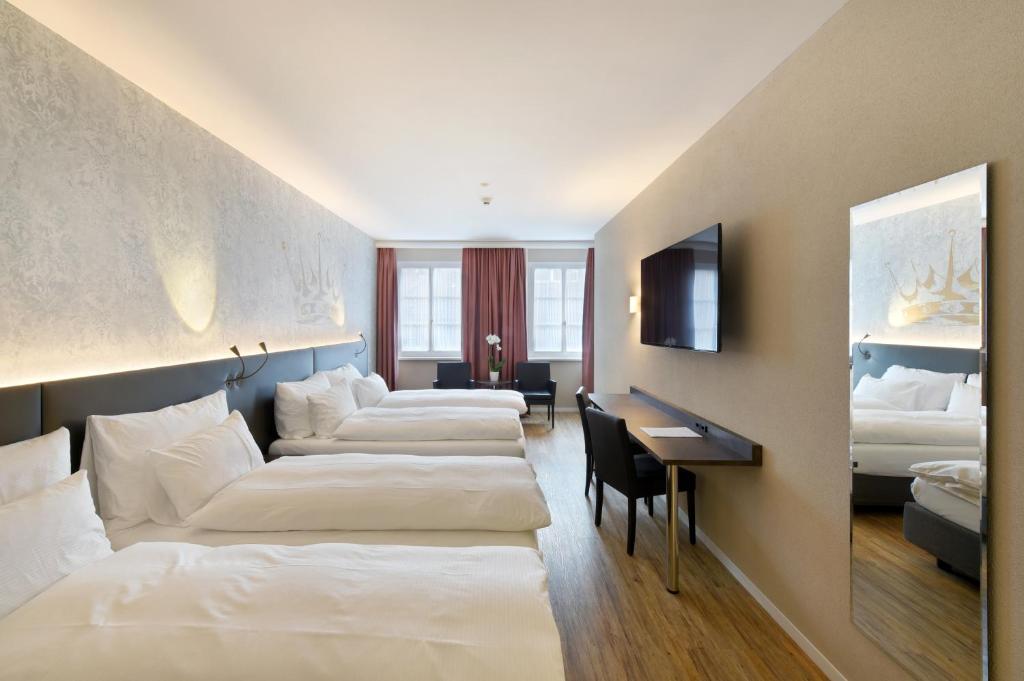 a hotel room with two beds and a desk at Altstadt Hotel Krone Luzern in Lucerne