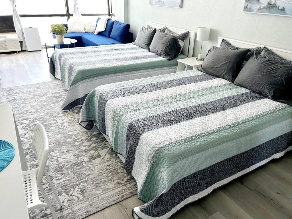 a bedroom with two beds and a chair in it at Daytona Ocean View Modern Studio in Daytona Beach
