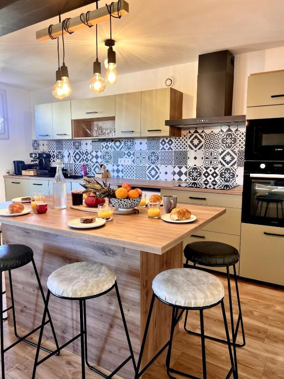 une cuisine avec un grand îlot en bois et des tabourets de bar dans l'établissement Plage à 15 min - Proche de la Gare - 6 personnes - 3 Chambres - Idéal Famille, à Narbonne