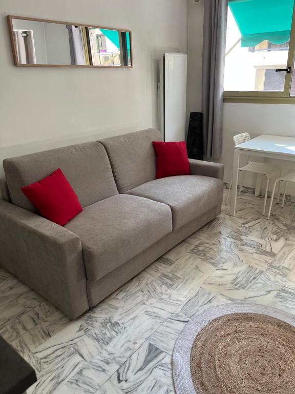 - un canapé avec deux oreillers rouges dans le salon dans l'établissement Studio meublé proche plages et vieille ville, à Antibes